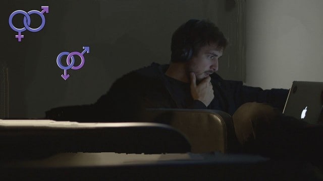 A man in a black sweater watching pornography secretly in his room using a laptop